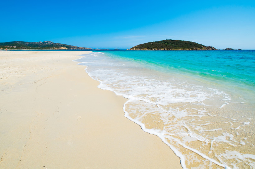 Sandstrand auf Sardinien mit türkisfarbenem Meer und vorgelagerter Insel