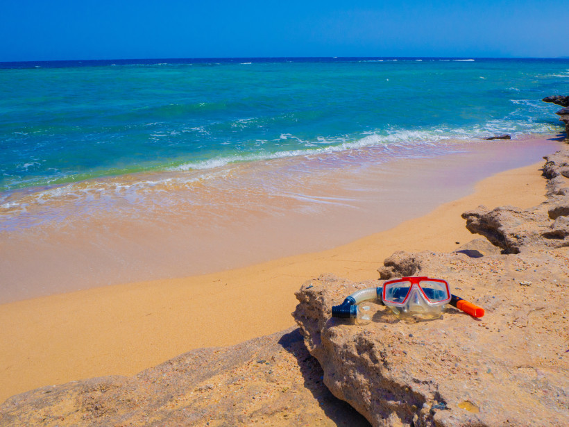 Sandstrand in Marsa Alam mit Schnorchelmaske auf einem Felsen am türkisblauen Meer