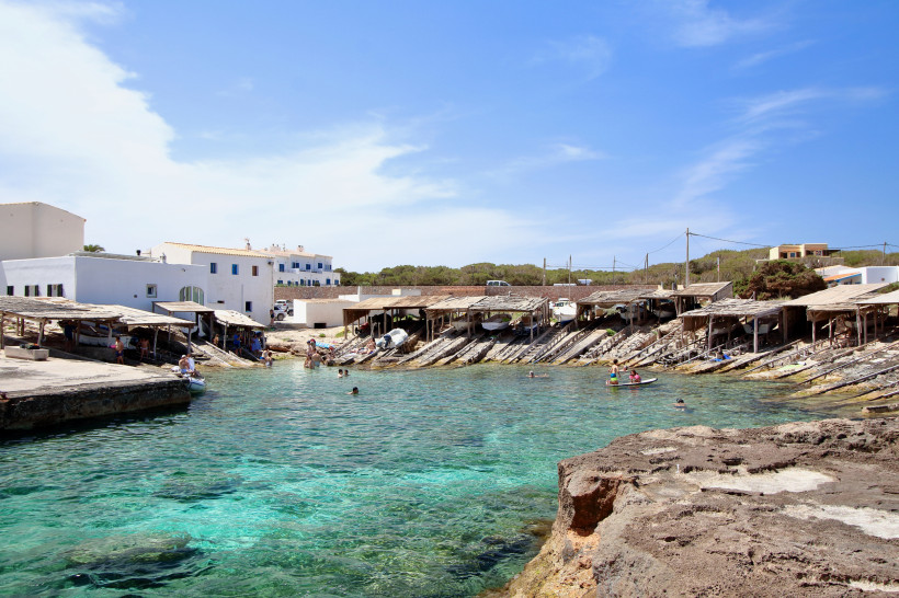Bootsschuppen und Badebucht mit klarem Wasser in Es Galo auf Formentera