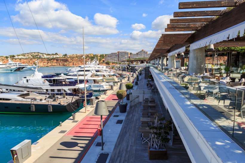 Port Adriano Marina mit Yachten am Steg und Promenade mit Restaurantterrasse