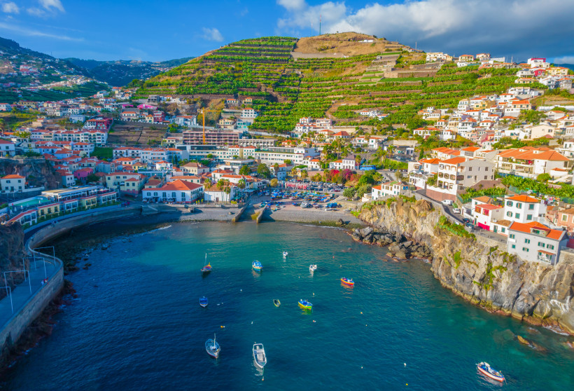 Luftaufnahme von Câmara de Lobos auf Madeira mit Hafen, Booten und terrassenförmigen Weinbergen an der Küste