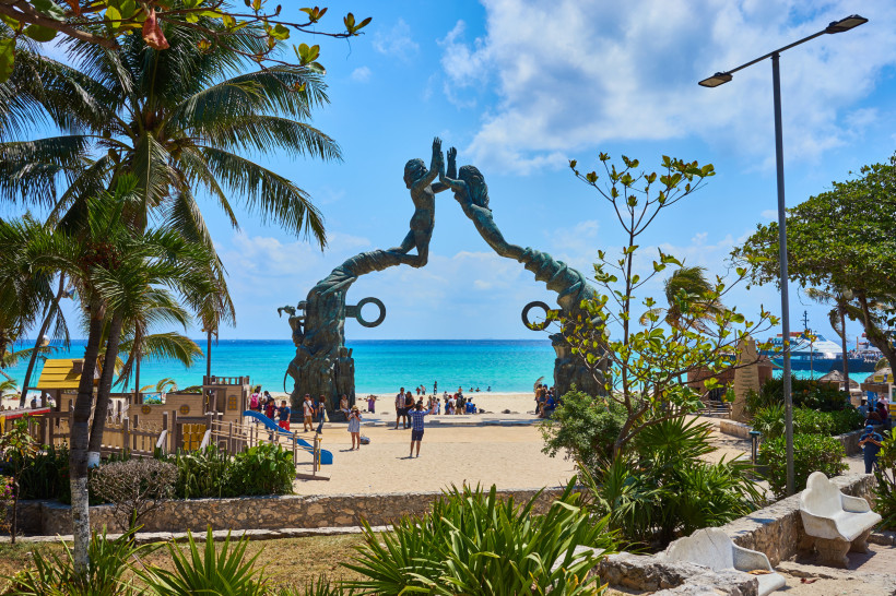  Ein beeindruckendes Monument am Strand mit Blick auf das türkisfarbene Meer, umgeben von Palmen und einem Spielplatz.