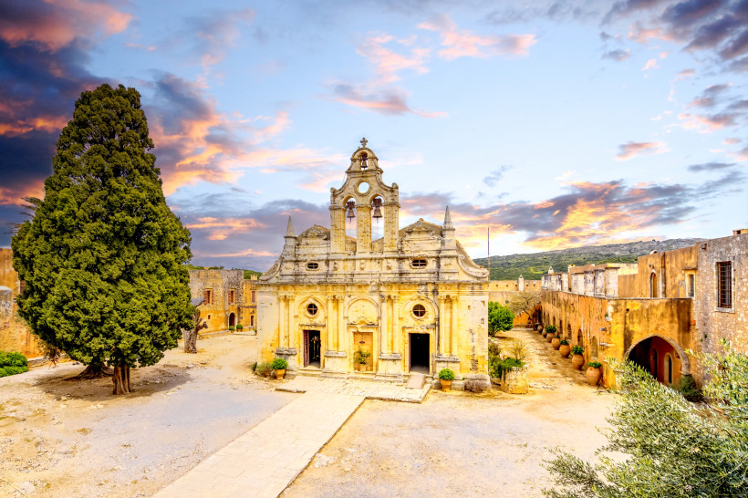 Kloster Arkadi: Klosterkirche und Innenhof bei Sonnenuntergang Fassade der Klosterkirche im Kloster Arkadi mit Innenhof und großer Zypresse bei Sonnenuntergang