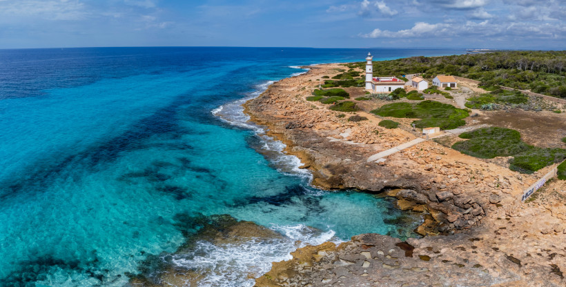 Felsige Küste bei Colonia de Sant Jordi mit Leuchtturm und türkisfarbenem Meer