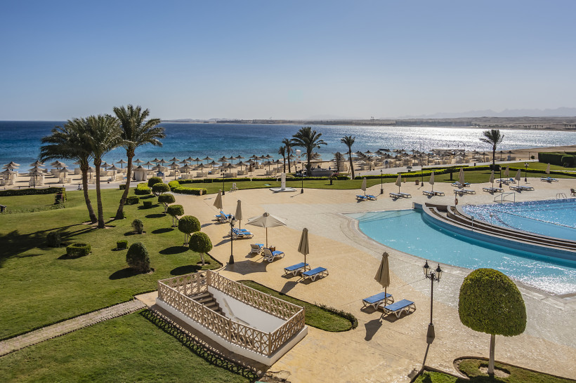 Große Hotelanlage mit Pool, Liegen und Palmen direkt am goldenen Sandstrand mit Blick auf das türkisfarbene Meer