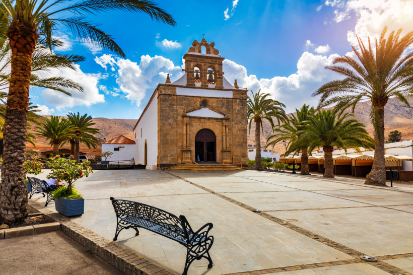 Iglesia de Santa María in Betancuria, Fuerteventura – historische Kirche an einem palmengesäumten Platz unter blauem Himmel