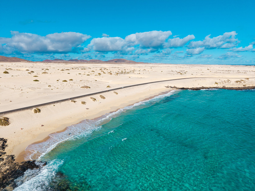 Küstenlandschaft bei Grandes Playas mit Sanddünen, Straße und türkisfarbenem Meer