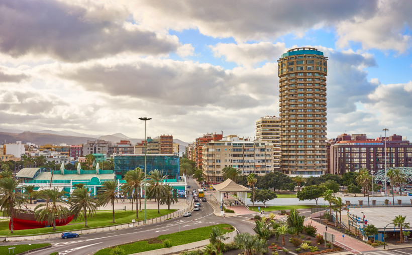 Stadtansicht von Las Palmas de Gran Canaria mit Hochhaus und Promenade Panoramablick auf Las Palmas de Gran Canaria mit modernen Gebäuden, Promenade, Palmen und Straßenverkehr unter bewölktem Himmel – urbanes Reiseziel auf den Kanaren.