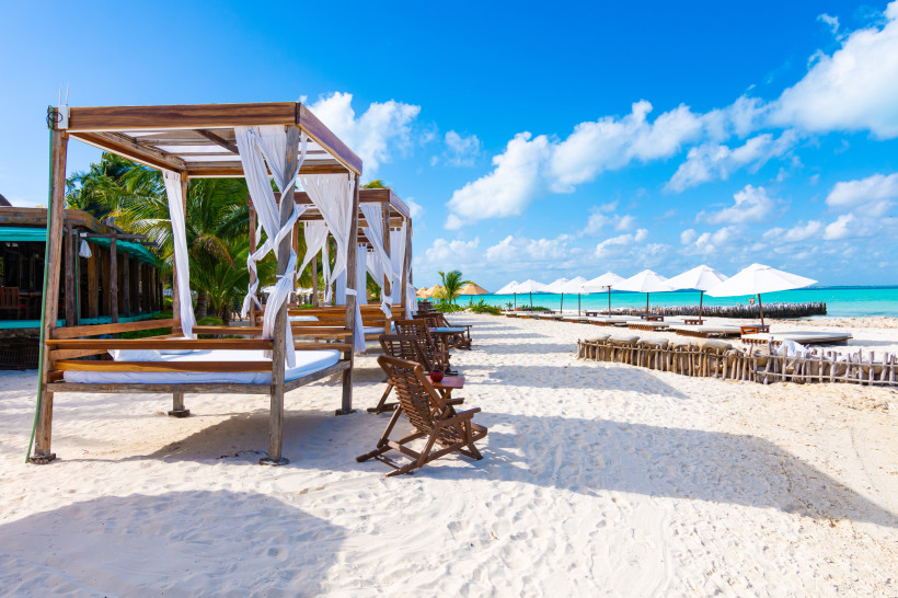 Weiße Sandstrände mit Bali-Betten, Liegestühlen und Sonnenschirmen auf Isla Mujeres in Mexiko – Karibikinsel für Ferien 2025/2026