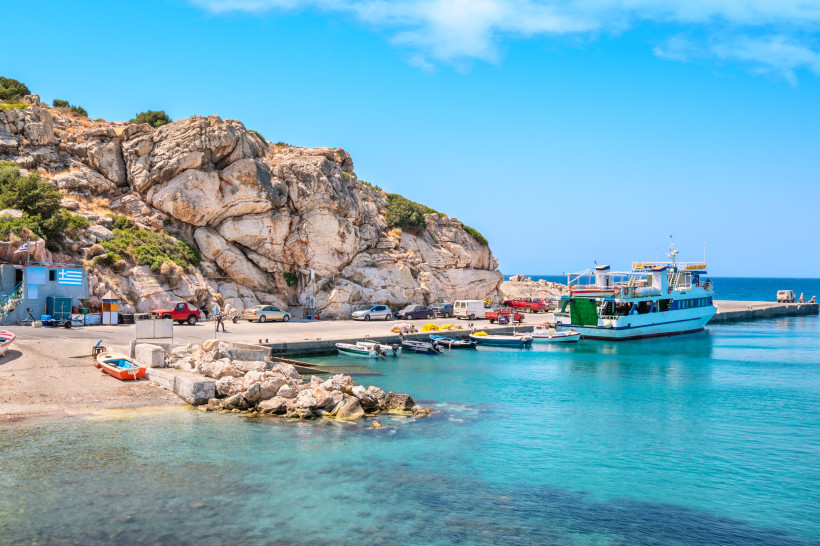 Kleiner Hafen auf Rhodos mit Felsklippen, Booten und türkisblauem, klarem Wasser – idyllische Küstenlandschaft