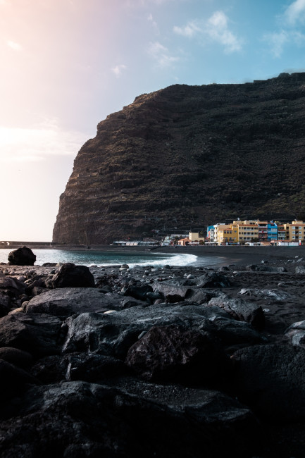 Playa de Tazacorte: Küstenansicht mit schwarzem Strand, Brandung und Ortschaft Playa de Tazacorte mit schwarzem Sandstrand, Felsenküste und Häusern am Ufer