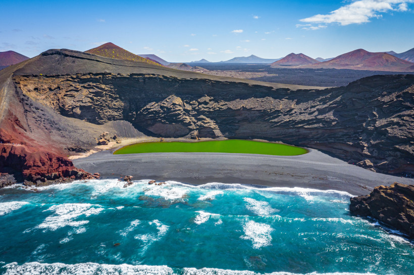 Lanzarote - El Golfo Luftaufnahme des grünen El Golfo Kratersees auf Lanzarote mit schwarzem Sandstrand, rotem Lavagestein und Atlantik im Hintergrund.