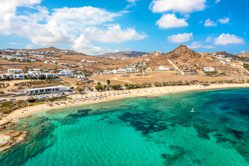 Mykonos - Kalafatis Luftaufnahme vom Kalafatis Beach auf Mykonos mit goldenem Sandstrand, Sonnenschirmen und klarem türkisblauem Wasser