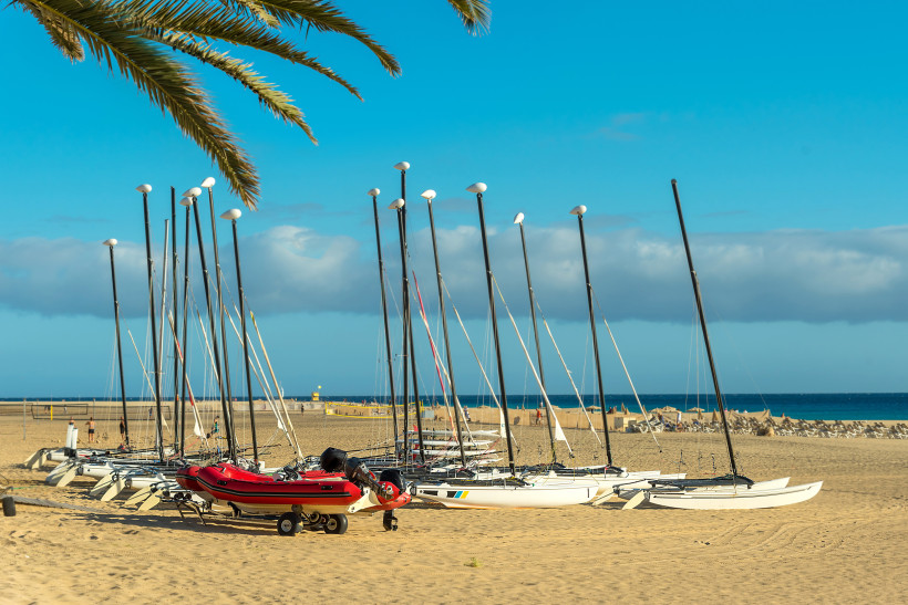 Katamarane mit aufgestellten Masten am Sandstrand von Morro Jable, im Hintergrund Meer und Himmel