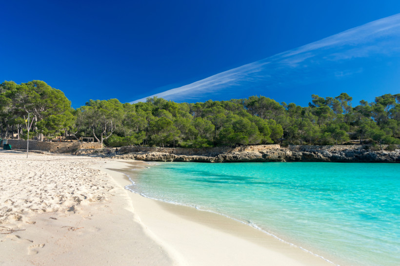 Mallorca - Cala Mondrago Strand von Cala Mondrago auf Mallorca, türkisblaues Wasser, blauer Himmel und Sonnenschein, üppige Vegetation im Hintergrund