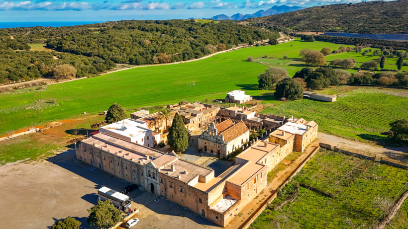 Luftaufnahme des Klosters Arkadi inmitten grüner Felder und hügeliger Landschaft