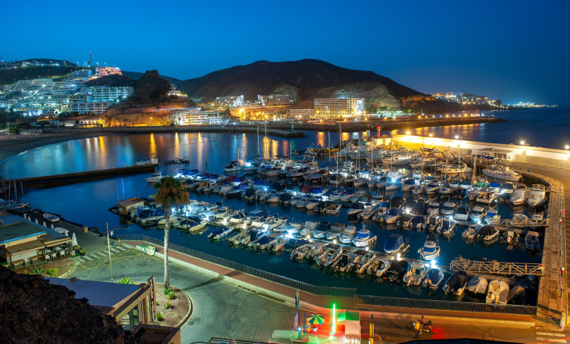 Marina in Puerto Rico bei Nacht mit zahlreichen Booten im Hafenbecken und beleuchteter Uferpromenade