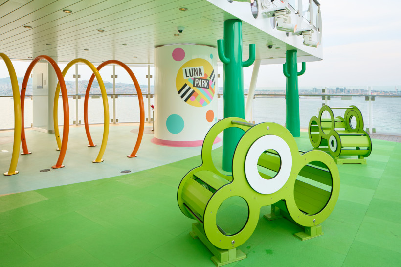 Luna Park auf der Costa Smeralda mit bunten Spielgeräten und Sitzbänken an Deck