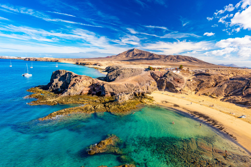 Playa de Papagayo Lanzarote – goldene Traumstrände Luftaufnahme der Playa de Papagayo auf Lanzarote mit goldenem Sandstrand, türkisblauem Meer, Felsklippen und Booten im Naturpark Los Ajaches