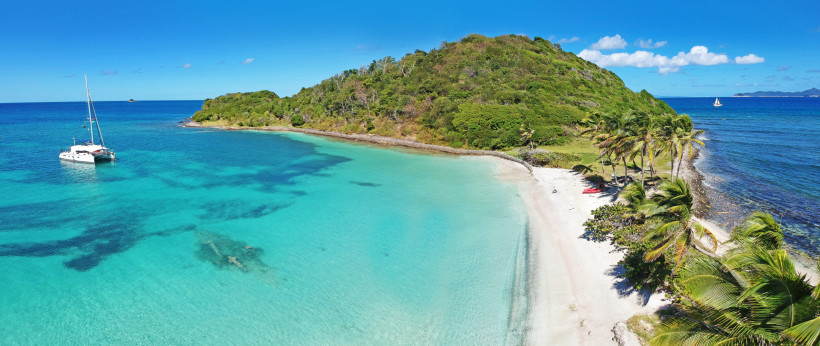 Karibischer Traumstrand mit Segelboot und türkisblauem Wasser