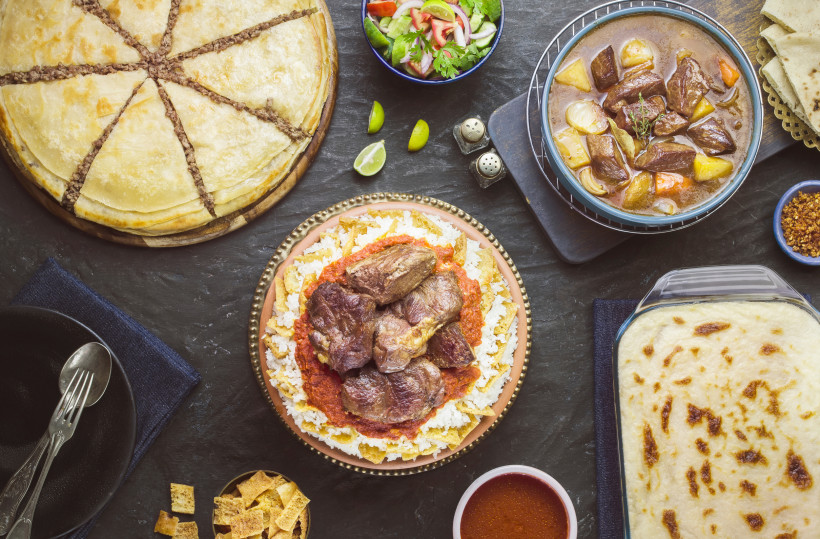 Ägypten - Sharm el Sheikh Ein gedeckter Tisch mit traditionellen arabischen Speisen. In der Mitte ein Teller mit Lammfleisch auf einer Basis aus geröstetem Brot, Reis und roter Sauce. Drum herum stehen weitere Gerichte wie ein großer Hackfleisch-Pie, Eintopf mit Rind und Gemüse, e