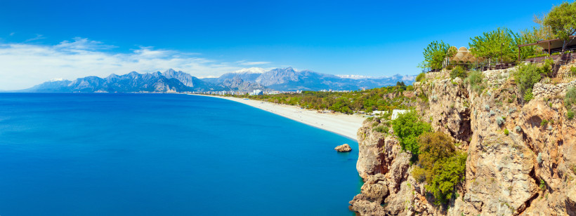Antalya im Sommer – Strandurlaub, Sonne und türkisblaues Meer Panoramablick auf die Küste von Antalya im Sommer mit blauem Meer, hellem Sandstrand und Taurusgebirge im Hintergrund – klassischer Sommerurlaub an der Türkischen Riviera