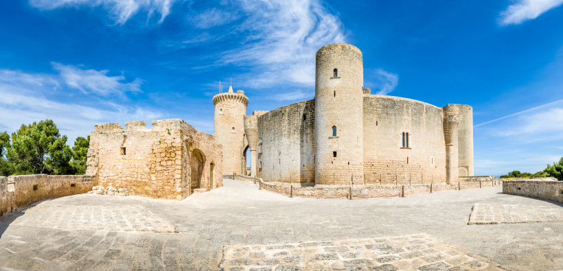 Castell de Bellver mit runden Türmen und Steinmauer unter blauem Himmel