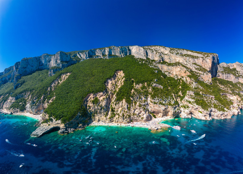 Luftaufnahme der Cala Mariolu auf Sardinien mit Booten im türkisfarbenen Meer, steilen Klippen und weißen Stränden – Highlight an der Ostküste Sardiniens
