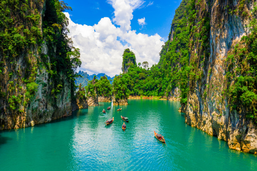 Longtail-Boote auf türkisfarbenem Wasser zwischen Kalksteinfelsen im Khao Sok Nationalpark in Südthailand