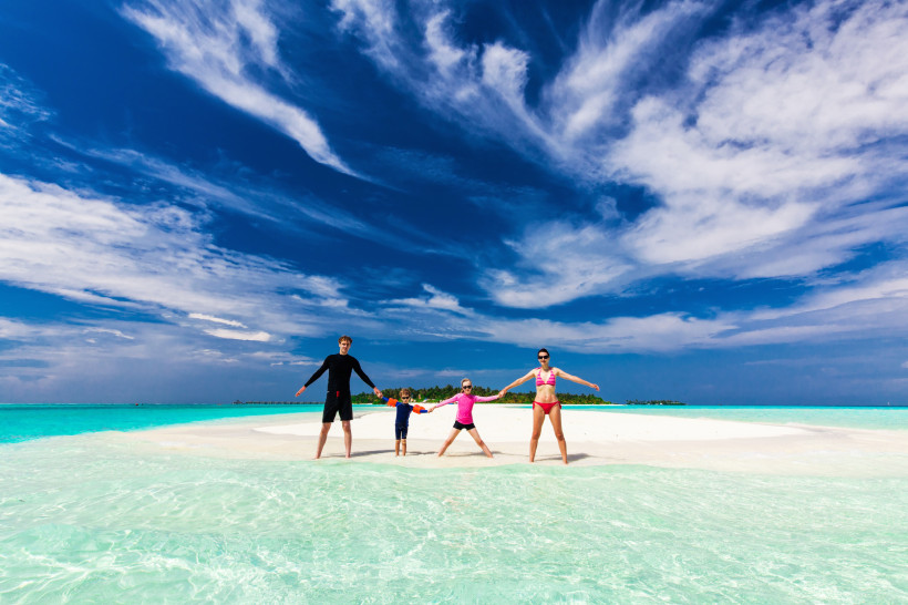 Malediven Eine Familie genießt ihren Urlaub auf einer traumhaften Sandbank mit kristallklarem Wasser und einem strahlend blauen Himmel. Ein perfekter Moment für unvergessliche Erinnerungen.