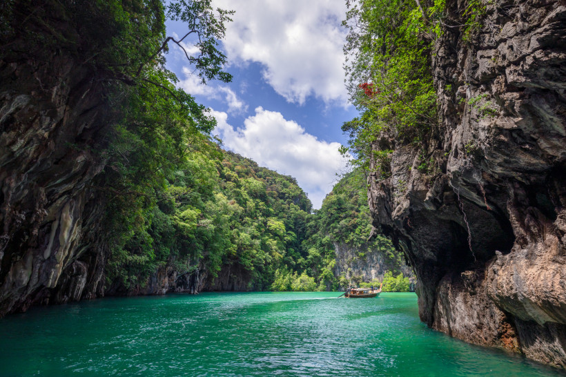 Lagune bei Krabi in Thailand mit smaragdgrünem Wasser, Karstfelsen und traditionellem Longtail-Boot.
