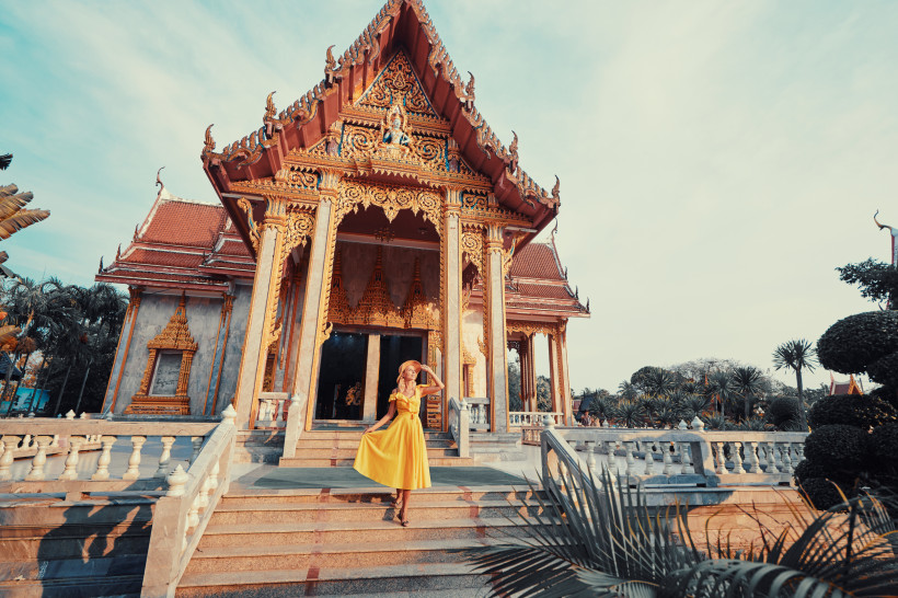 Wat Chalong Phuket – Besuch des wichtigsten Tempels auf der Insel Frau in gelbem Kleid vor dem Wat Chalong in Phuket, dem wichtigsten buddhistischen Tempel der Insel, bei warmem Sonnenlicht.