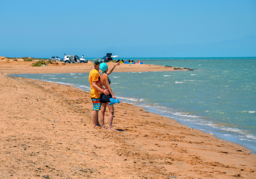 Paar steht am breiten Sandstrand von Hurghada und blickt gemeinsam aufs Meer