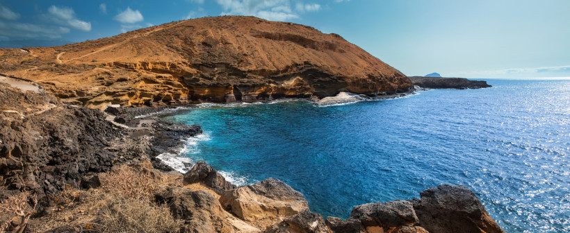 Felsige Küstenbucht bei Costa del Silencio mit türkisblauem Meer und braunen Klippen