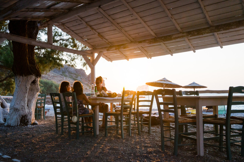 Kreta: Familienfreundliche Taverne direkt am Meer Familien sitzen bei Sonnenuntergang in einer entspannten Strandtaverne auf Kreta – typisch für ruhige Urlaubsabende wie in Stalida