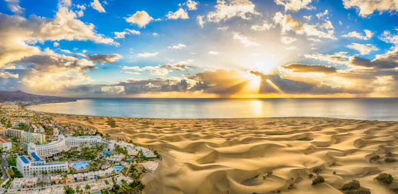 Sonnenuntergang über den Dünen von Maspalomas – Gran Canaria Panorama mit Sanddünen von Maspalomas und Sonnenuntergang über dem Atlantik im Süden Gran Canarias, mit Hotels und Küste im Vordergrund