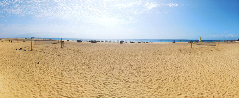 Weitläufiger Sandstrand von Jandía an der Südküste Fuerteventuras Panoramablick über den langen Sandstrand von Jandía auf Fuerteventura mit Beachvolleyballfeldern, Liegen und türkisblauem Meer