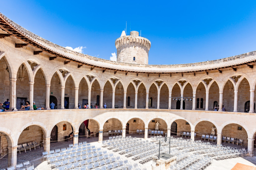 Festung Castell de Bellver, Mallorca Innenhof des runden gotischen Castell de Bellver in Palma de Mallorca mit Arkaden und Turm bei blauem Himmel