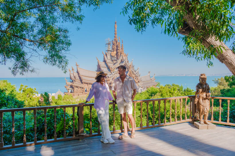 Pattaya Sehenswürdigkeiten – Sanctuary of Truth mit Aussicht auf das Meer Paar mit Blick auf den hölzernen Sanctuary of Truth Tempel in Pattaya, Thailand – beliebte kulturelle Sehenswürdigkeit am Meer.
