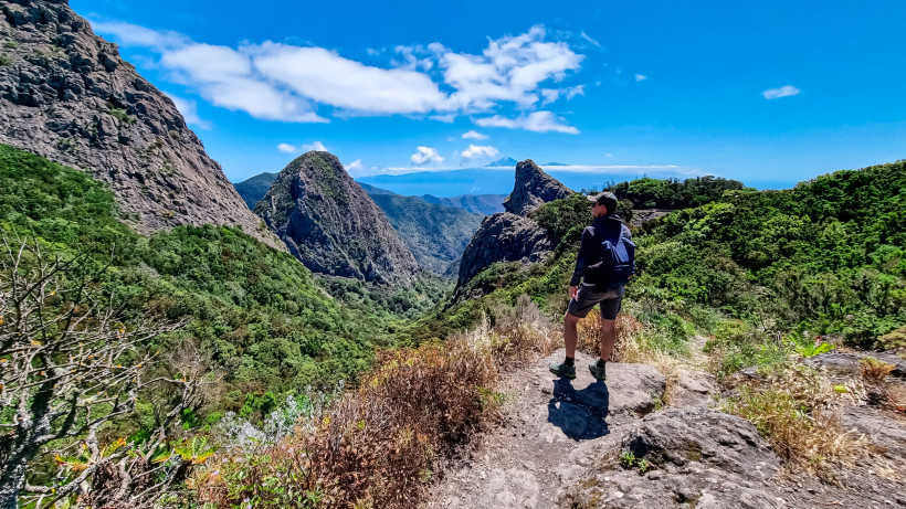 Berglandschaft auf La Gomera mit Wanderweg, Felsgipfeln und Blick über ein grünes Tal bis zum Meer
