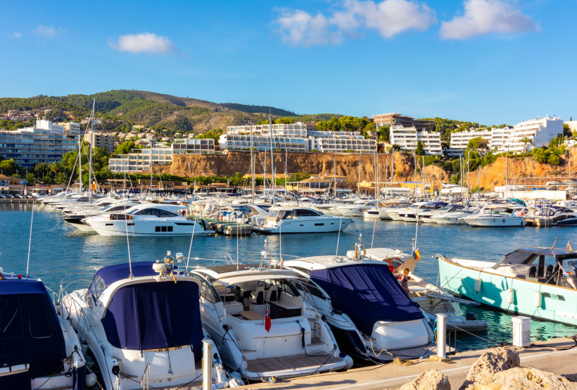 Yachthafen Puerto Portals mit zahlreichen Motor- und Segelyachten, im Hintergrund Wohngebäude am Hang
