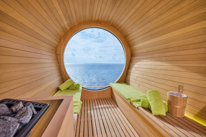 Mein Schiff Relax: Fasssauna mit Panoramafenster und Meerblick Innenansicht einer Fasssauna auf der Mein Schiff Relax mit rundem Panoramafenster und Blick aufs Meer