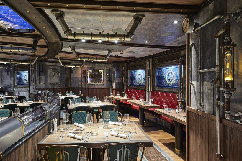 Interieur des Restaurants „Time Machine“ auf der AIDAnova mit industriellem Design, gedeckten Tischen und roter Sitzbank