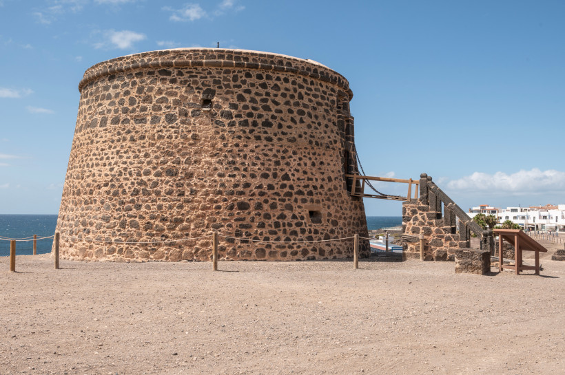 Castillo del Tostón, runder Steinturm an der Küste unter blauem Himmel
