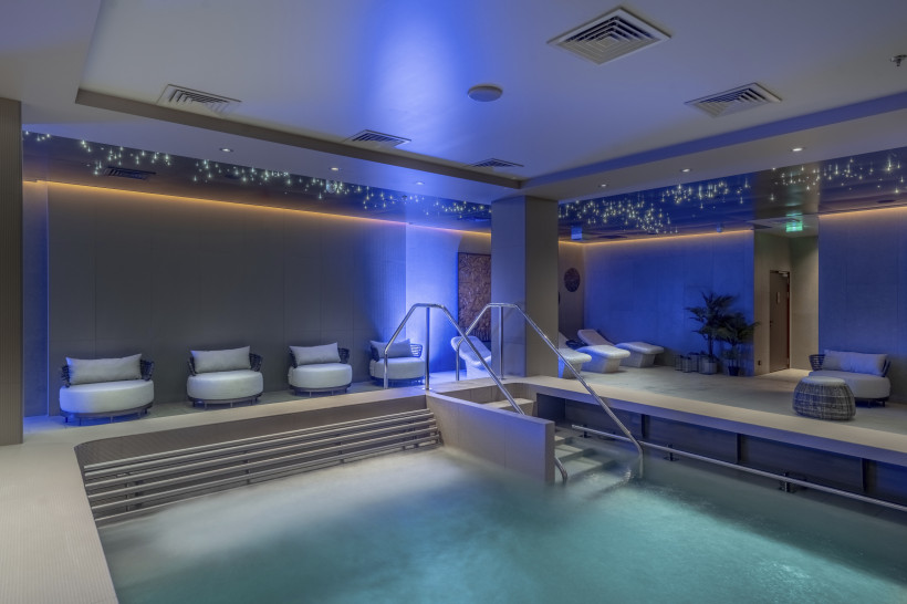 Innenbereich der MSC Aurea Spa auf der MSC World Europa mit Pool, Treppe und Liegen