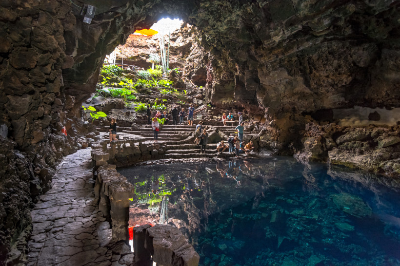 Jameos del Agua – Spektakuläre Vulkanhöhle mit unterirdischer Lagune Vulkanhöhle Jameos del Agua auf Lanzarote mit klarer Lagune, Natursteinstufen und Besuchern in der Lavagrotte