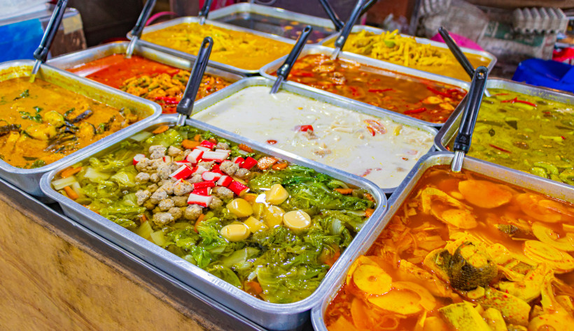 Auswahl an traditionellen thailändischen Currys in leuchtenden Farben, frisch zubereitet auf einem Streetfood-Markt in Koh Samui, Thailand.