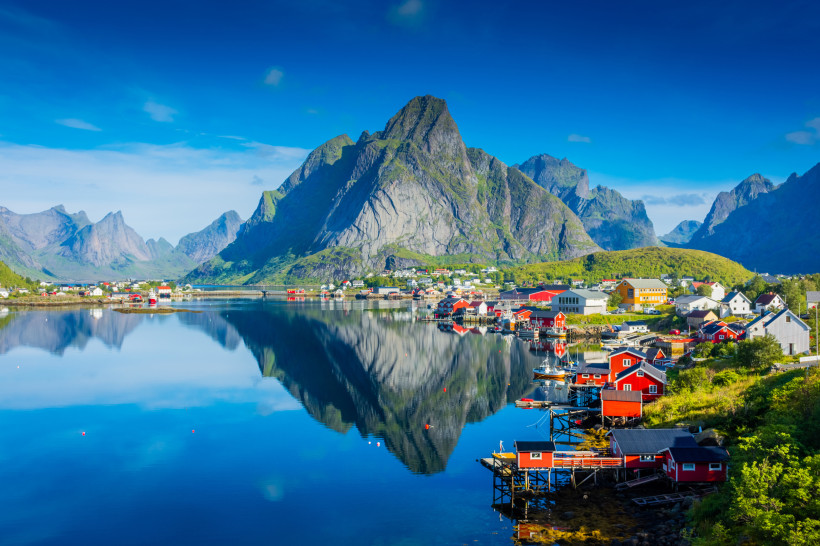 Fjordlandschaft auf den Lofoten mit steilen Bergen, Küstendorf und Spiegelung im ruhigen Wasser