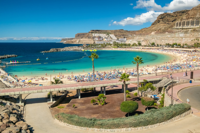 Bucht und Sandstrand von Puerto Rico auf Gran Canaria mit Liegen, Sonnenschirmen und Promenade