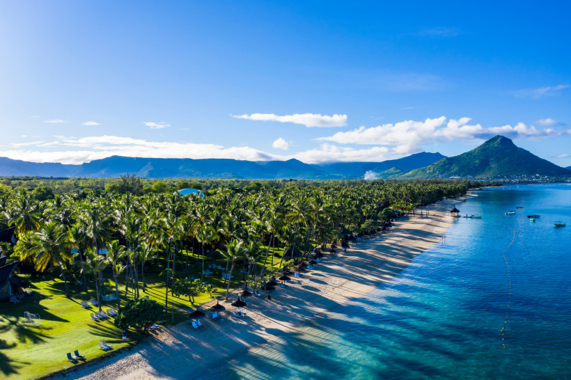 Luftaufnahme des Strandes von Flic en Flac auf Mauritius mit Palmen, türkisfarbenem Wasser und Blick auf den Berg Le Morne